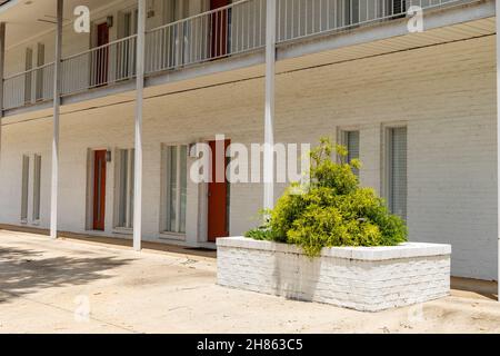 Edificio di appartamenti generico, mattone dipinto di bianco con porte rosse, grande piantatrice di mattoni, aspetto orizzontale Foto Stock