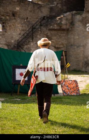 Persone in abiti medievali con archi sul territorio del castello Foto Stock