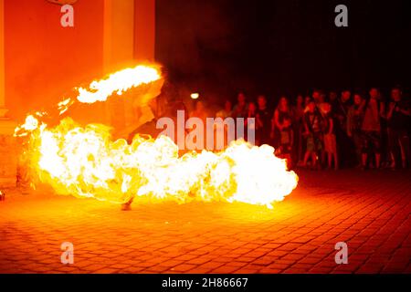 Un ragazzo fa uno spettacolo di fuoco sulla strada di notte intorno ad una folla di persone Foto Stock