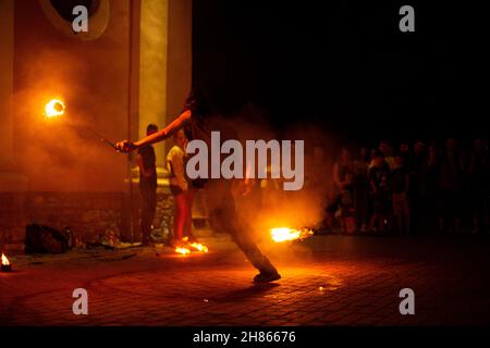 Un ragazzo fa uno spettacolo di fuoco sulla strada di notte intorno ad una folla di persone Foto Stock