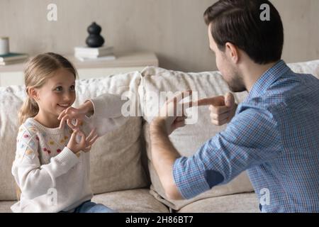 Felice adorabile bambino piccolo usando il linguaggio dei segni, comunicante con il padre. Foto Stock