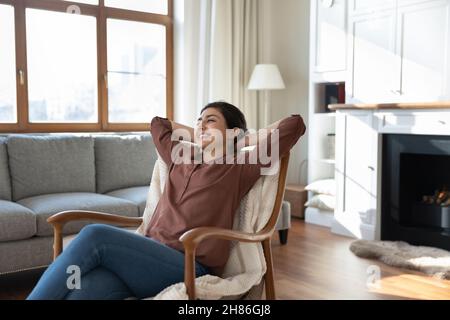 Tranquilla e felice giovane donna indiana rilassante in comoda poltrona. Foto Stock