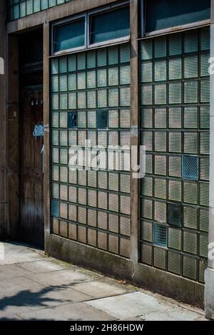 Parete in mattoni di vetro davanti ad un vecchio edificio di uffici a Londra Foto Stock