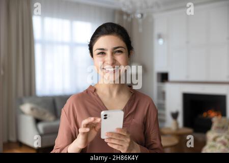 Ritratto di donna indiana sorridente che tiene lo smartphone nelle mani. Foto Stock