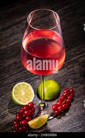 Bicchiere con bevanda al ribes rosso su sfondo di legno Foto Stock