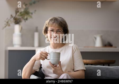 Donna più anziana felice in occhiali godendo buon mattino Foto Stock
