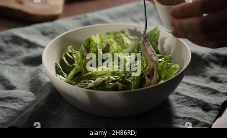 man pour medicazione sopra le foglie di romaine in ciotola bianca larga foto Foto Stock