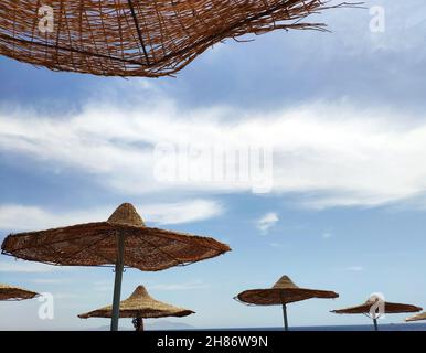 Ombrelloni solari sulla spiaggia su sfondo cielo blu, vacanze estive sfondo carta da parati Foto Stock