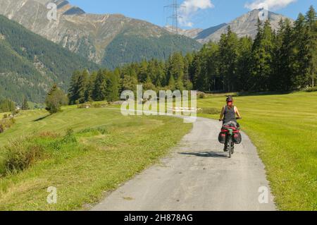 Ciclista femmina sul Inn rotta vicino Susch (o SUS) Zernez, comune nel distretto di Inn nel cantone svizzero dei Grigioni. Modello di rilascio disp Foto Stock