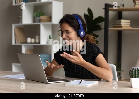 Interprete ispanico femminile in cuffia che lavora in remoto parlare utilizzare il laptop Foto Stock