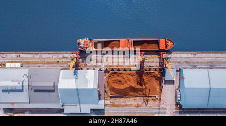 Caricamento della sabbia sulla nave nel porto di carico, materiali da costruzione per le regioni difficili da raggiungere. Foto Stock