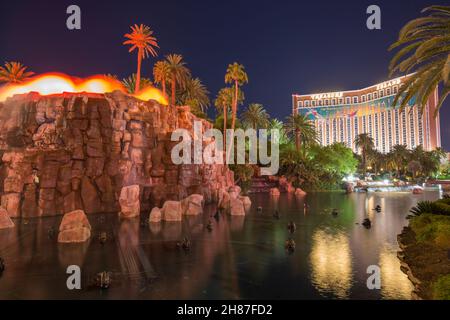 Las Vegas, Nevada, Stati Uniti. Vista notturna attraverso il lago illuminato fuori dal Mirage Resort and Casino, vulcano artificiale che erutta da scogliere di roccia rossa. Foto Stock