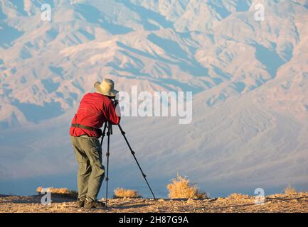 Death Valley National Park, California, USA. Fotografo a Dante's View che scatta la lontana gamma Panamint con cavalletto dal bordo della scogliera, alba. Foto Stock