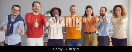 Felice sorridente gruppo di uomini d'affari che mostrano i pollici insieme alla fotocamera Foto Stock