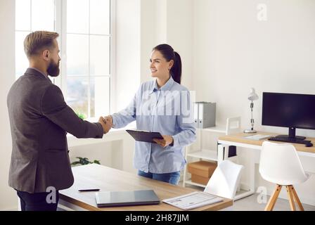 Responsabile bancario femminile che si scambiano la stretta di mano con il cliente business dopo la riunione in ufficio Foto Stock