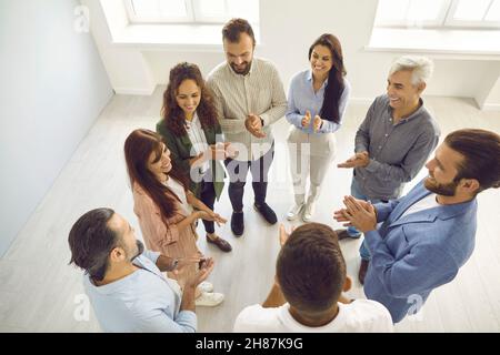 Le persone si trovano in circolo nel gruppo di contatto e si applaudono per sostenere la loro donna leader o collega. Foto Stock