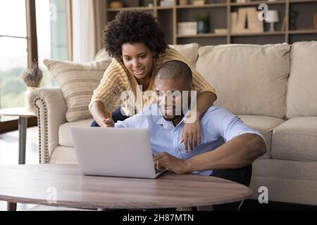 La giovane coppia africana felice si è concentrata sullo schermo del portatile che guarda il film Foto Stock