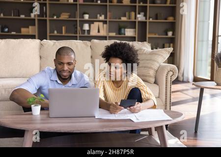 Coppia millenaria afroamericana che usa un computer portatile a casa Foto Stock