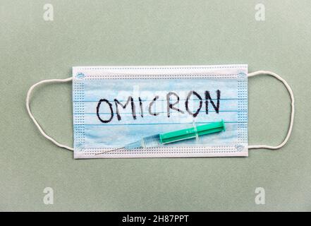 Nuovo concetto Omicron di mutazione di Coronavirus Covid-19. Maschera medica, siringa e testo con lettere Omicron. Foto Stock