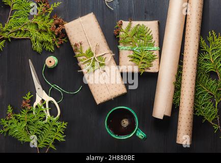 Regali di Natale avvolti in carta artigianale e tazza di caffè nero Foto Stock