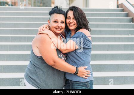 Due sorelle gemelle adulte abbracciano. Stili diversi Foto Stock