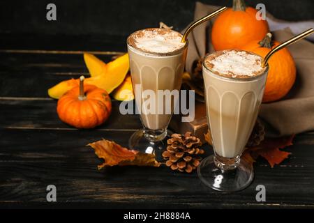 Bicchieri di gustoso latte di zucca su sfondo di legno nero Foto Stock