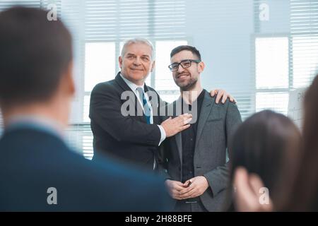 Project Manager si congratula con il miglior dipendente durante una riunione con il gruppo di lavoro. Foto Stock