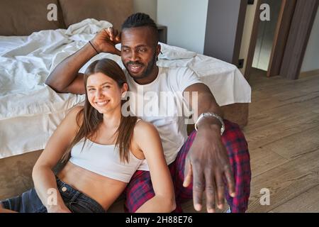 Romantica coppia mista seduta al piano della camera da letto Foto Stock