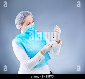 l'infermiera giovane in una maschera medica si pone di fronte alla macchina fotografica su un tema medico Foto Stock