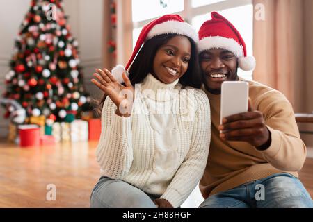 Felice famiglia nero festivo utilizzando cellulare fare videocall su Natale Foto Stock