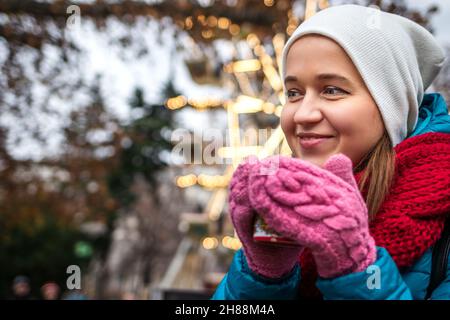 Giovane donna che beve VIN brulé al mercatino di natale di Rathausplatz, Vienna, Austria. Buon turista godendo la vacanza durante le vacanze di natale Foto Stock