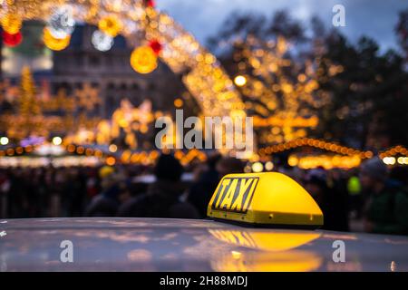 Taxi auto taxi in strada città vicino al mercato di Natale in Rathausplatz, Vienna, Austria. Primo piano cartello taxi giallo sul tetto auto di notte. Trasporto pubblico Foto Stock