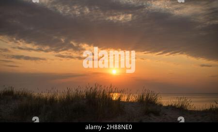 Caldo tramonto nuvoloso su una spiaggia ricoperta di erba a Jurmala Lettonia Foto Stock