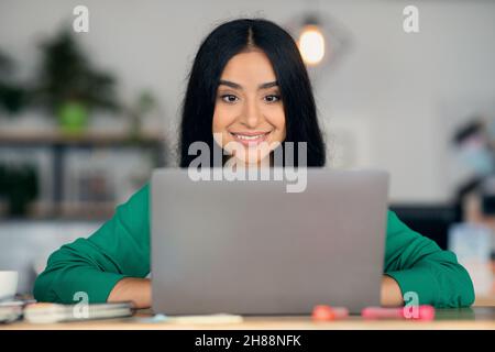 Ritratto di primo piano della giovane freelance indiana che lavora su un notebook Foto Stock