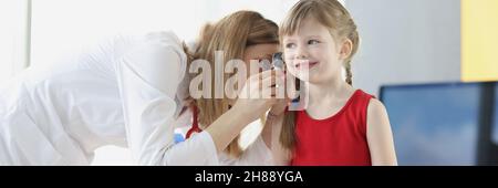 Il medico esamina le orecchie del bambino con un otoscopio nel closeup dell'ufficio del medico Foto Stock