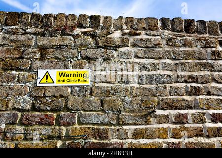 Cartello "Warning anti Climb Paint" sul muro di un parco pubblico Foto Stock