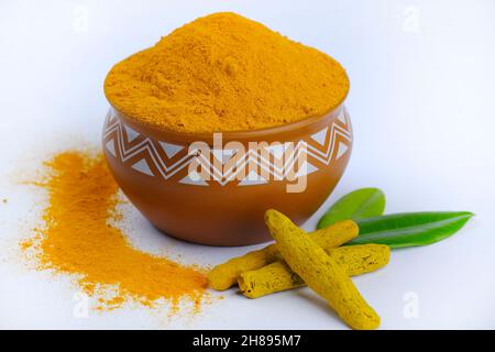 Polvere di curcuma (curcumino), polvere di curcuma in ciotola accanto alle radici di curcuma e polvere di curcuma sparsa su una superficie, isolata su sfondo bianco. Foto Stock