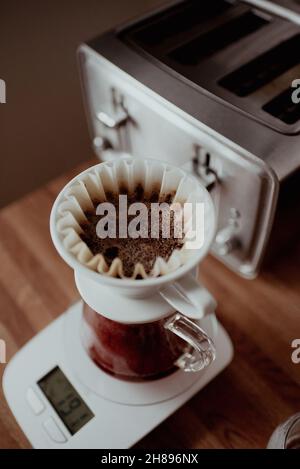 Versare l'acqua calda dal bollitore a collo d'oca nella macchina per caffè pour-over, estrazione lenta del caffè, caffè filtrato appena fatto, per preparare il caffè a casa Foto Stock