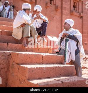 Lalibela, Etiopia - 23 maggio 2021: Gruppo di vecchi sacerdoti fuori di una chiesa, indossando abiti bianchi e turbanti Foto Stock