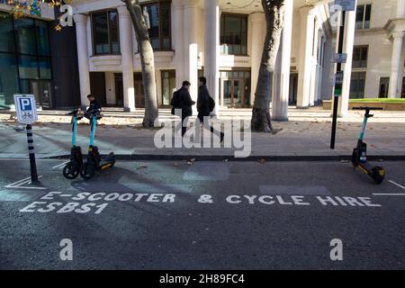 Due scooter elettrici di livello uno in una baia parzialmente vuota di scooter e noleggio biciclette nella città di Londra Foto Stock