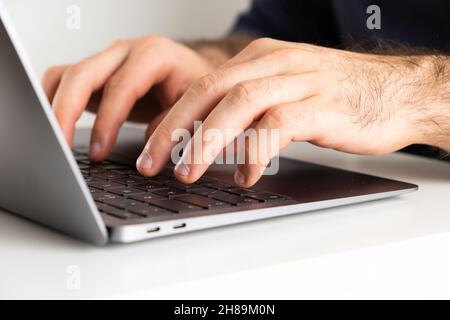 Mans mani su una tastiera del computer digitando un testo. Homeoffce o freelance che lavorano a casa. Foto Stock