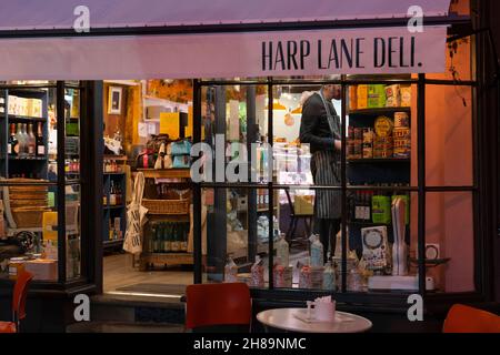 Harp Lane Deli illuminato di notte con prodotti alimentari nelle sue vetrine nel centro di Ludlow. Shropshire, Regno Unito Foto Stock