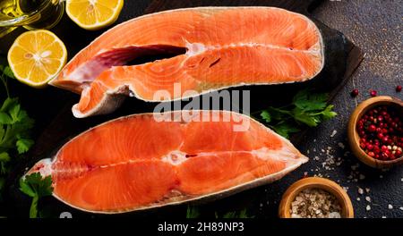Bistecche di salmone al rum crudo con spezie, erbe, sale e limone su sfondo di pietra antica. Vista dall'alto dello spazio di copia. Foto Stock