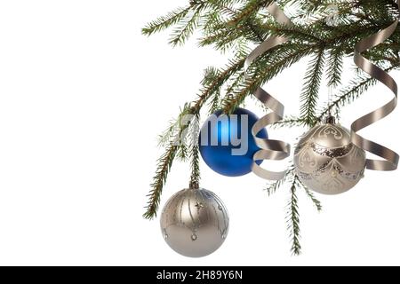 Decorazioni di Natale. Decorato albero di natale ramo con tre palle e serpentine nastri isolati su sfondo bianco Foto Stock