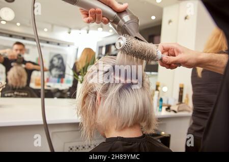 Uomo che piega i capelli con asciugacapelli e spazzola rotonda. Cura dei  capelli a casa dopo il barbiere. Moda uomo e capelli moderni Foto stock -  Alamy