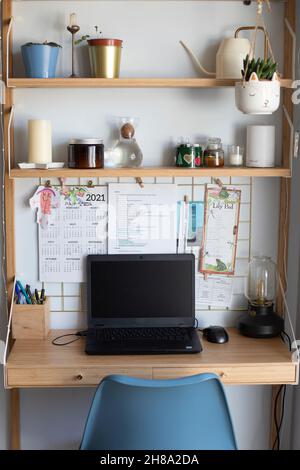 Piccola stazione remota per uffici domestici, area di lavoro, con computer portatile, piante domestiche, scheda metallica, candele e lampada da tavolo. Scatto verticale. Vista frontale. Foto Stock