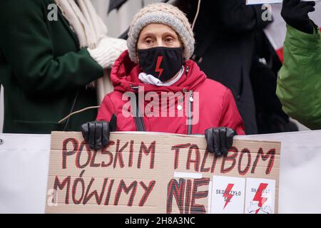 Danzica, Polonia. 28 novembre 2021. Un manifestante che indossa una maschera con un simbolo di fulmine tiene un cartello con la scritta "diciamo no ai talebani polacchi" durante una protesta a Danzica.i manifestanti si sono riuniti nella città vecchia di Danzica contro l'inasprimento delle sanzioni per la cessazione della gravidanza e l'introduzione di un registro di gravidanza in Polonia. Secondo le sanzioni, la cessazione della gravidanza deve essere trattata allo stesso modo dell'omicidio. Il pubblico ministero ha accesso al registro. Credit: SOPA Images Limited/Alamy Live News Foto Stock