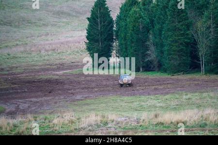 Blu e argento Suzuki Jimny 4x4 fuoristrada guidato intorno a una distesa fangosa nel bosco, Wiltshire UK Foto Stock