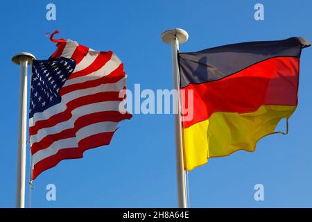 Le bandiere nazionali degli Stati Uniti d'America e della Germania adiacenti sono visibili su due alberi ed entrambe possono essere viste su un backgr blu chiaro Foto Stock
