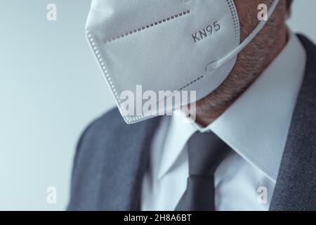 Elegante uomo d'affari che indossa maschera respiratoria protettiva KN95 durante le pandemie di Covid-19, fuoco selettivo Foto Stock